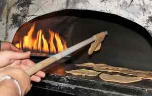 flat unleavened bread being cooked in oven with fire